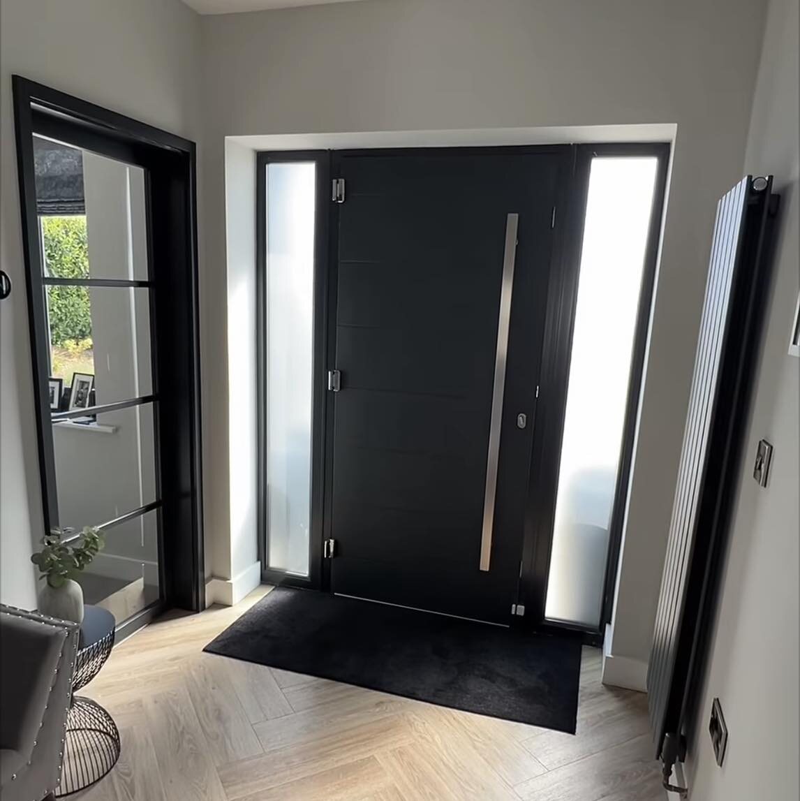 A black composite front door with frosted side screens, seen from the hall