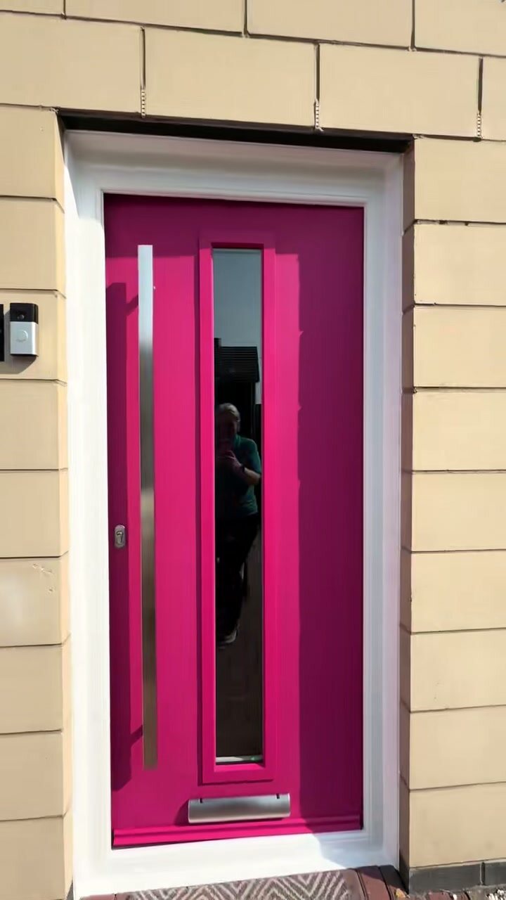 A pink composite front door in a sandstone reveal
