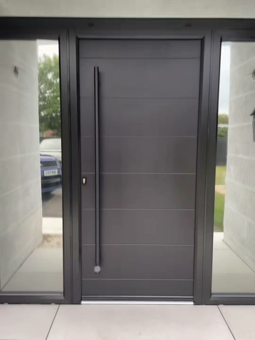 An all-black Virtu-Ali composite front door with a long bar handle, straight on