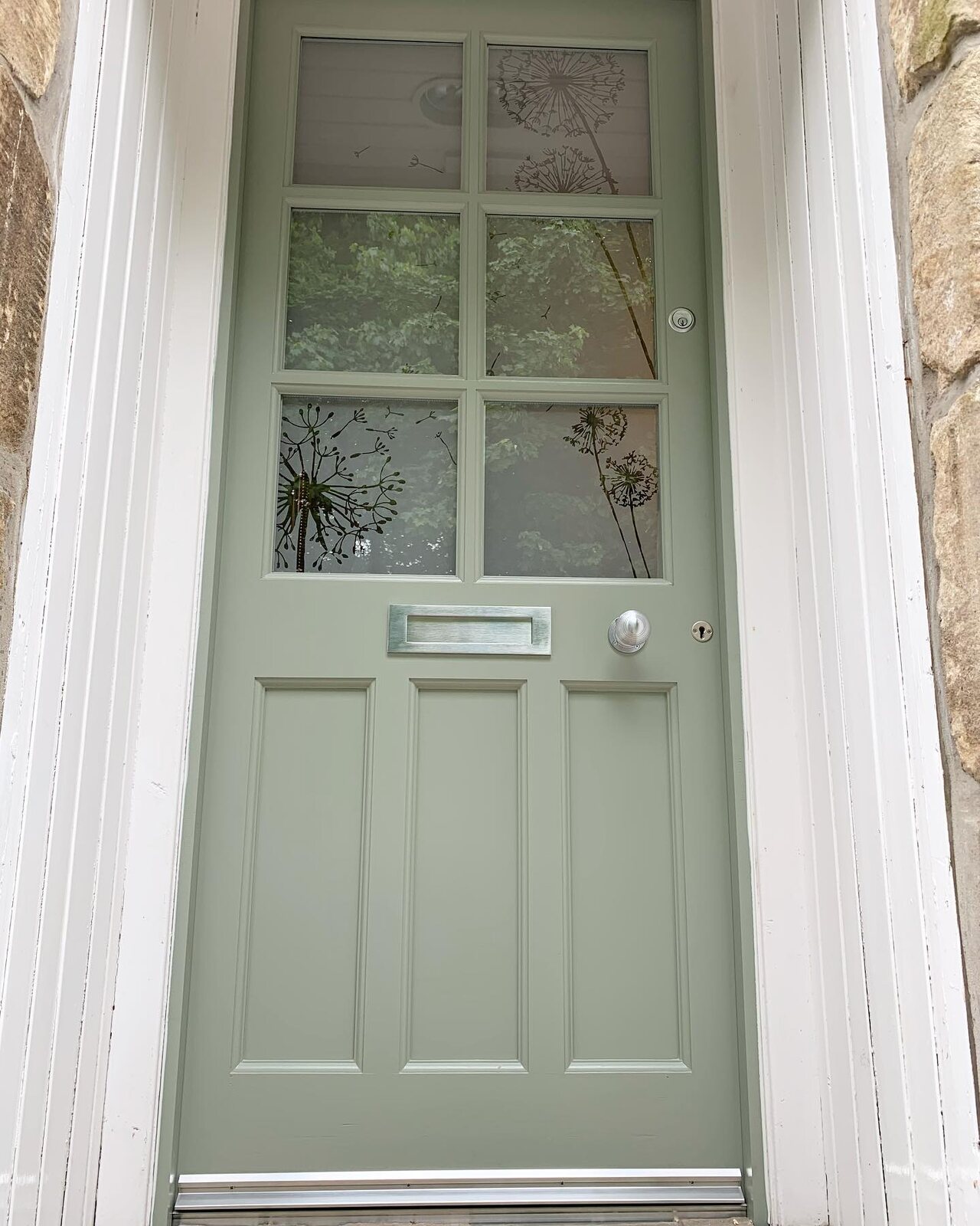A sage-green traditional door with cotton flower etched glass panes, seen from outside