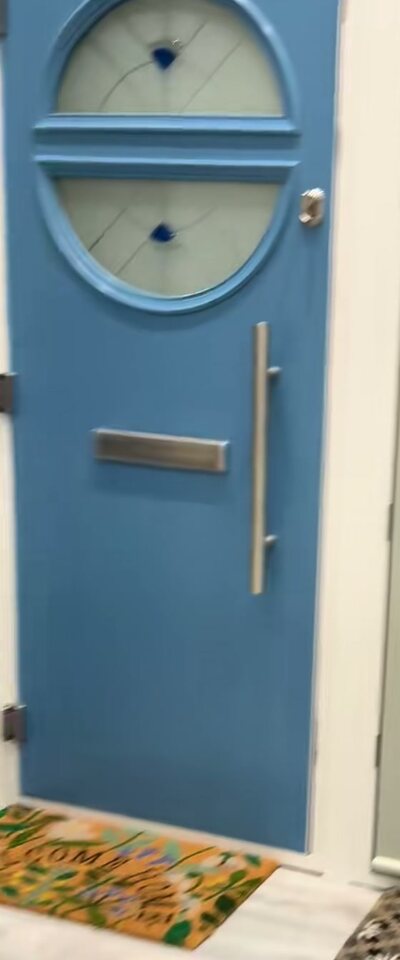 A blue composite front door with round glazing on the showroom wall