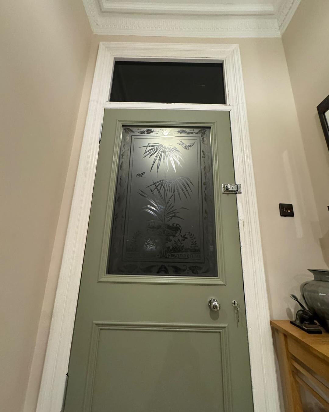 The same sage door from inside the hall, the etching lit from outside