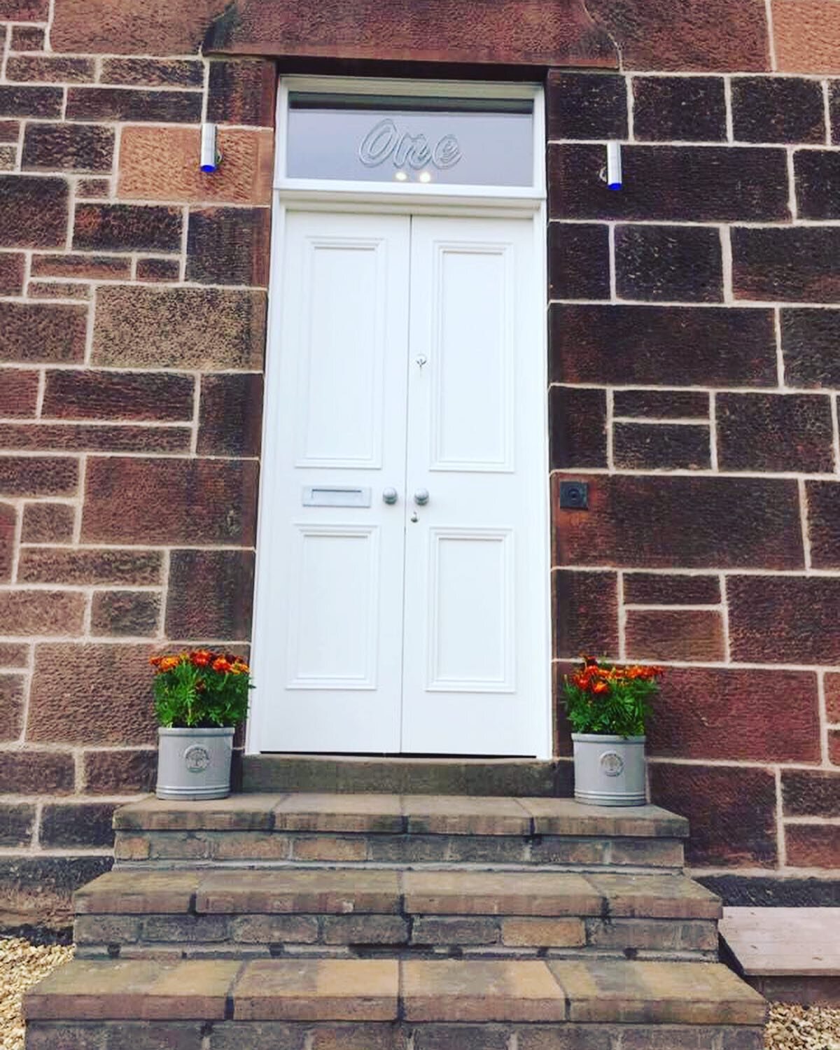 White satin hardwood double storm doors on a brown sandstone front