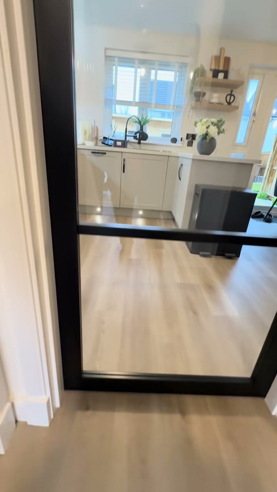 A single black glazed door, looking through into a kitchen