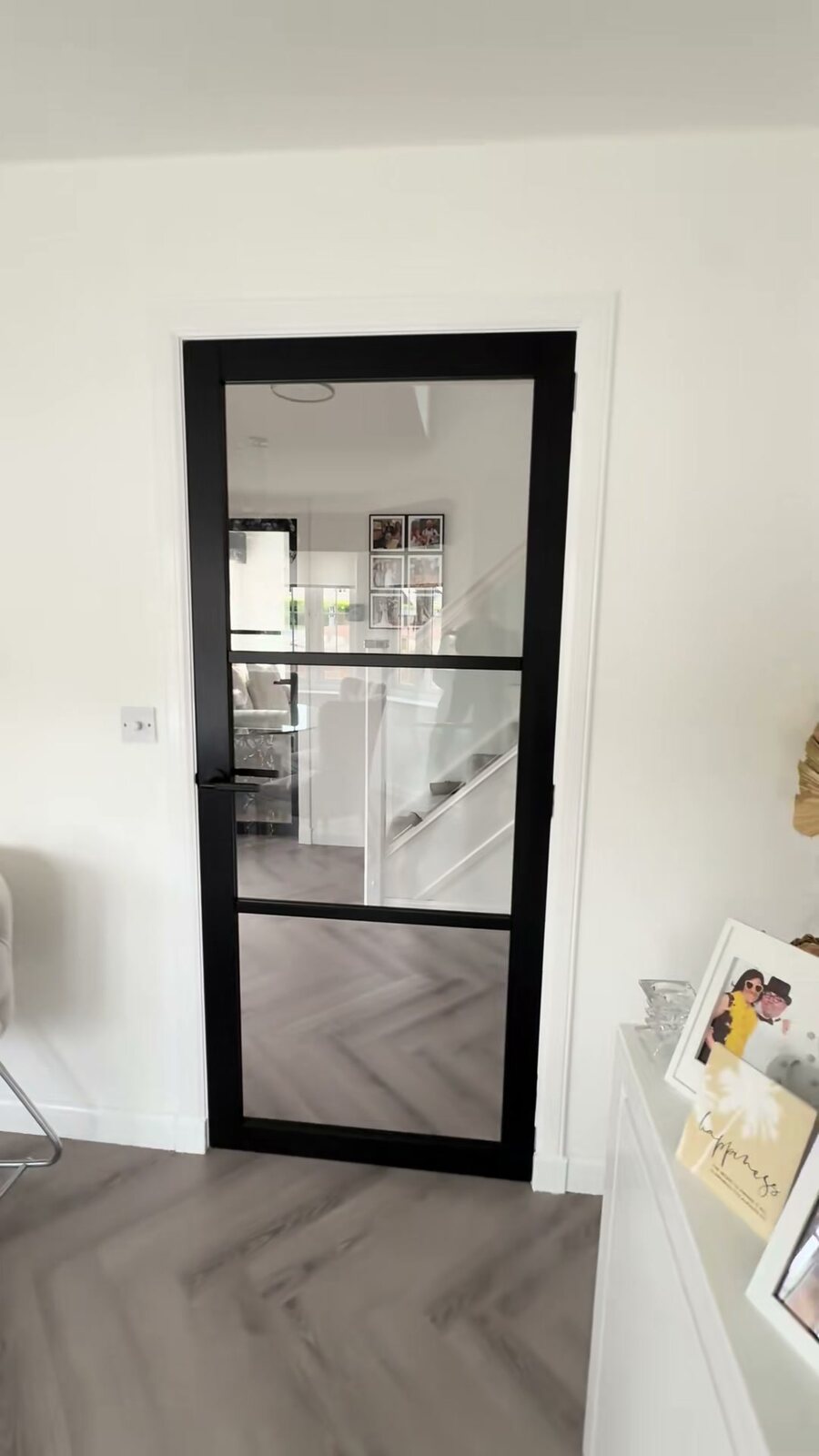 A black Camden glazed door in a white room, on a herringbone floor