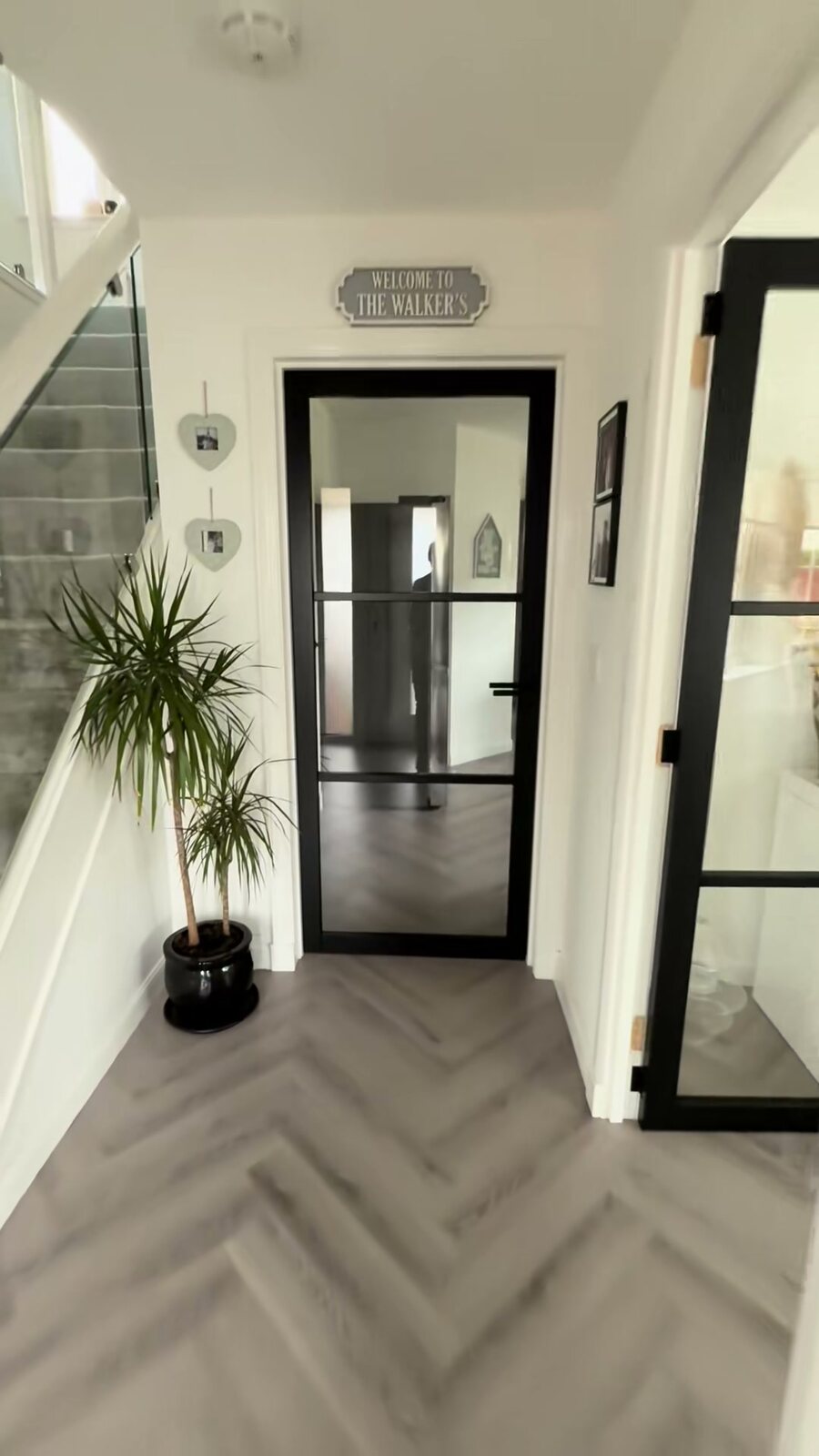 Two black glazed doors in a white hall with a herringbone floor