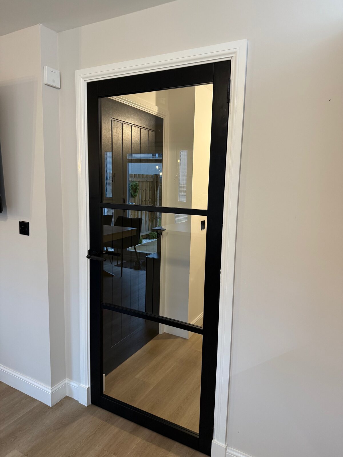 A black urban glazed door with smoked glass into a dining area
