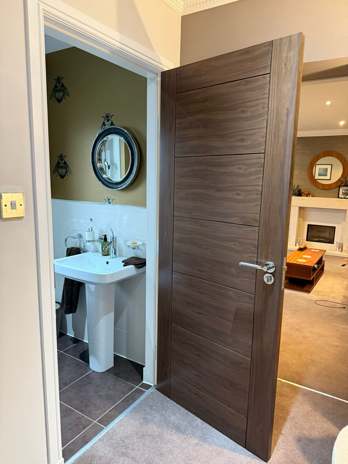 A pre-finished walnut internal door with horizontal grooves, open between a hall and a bathroom