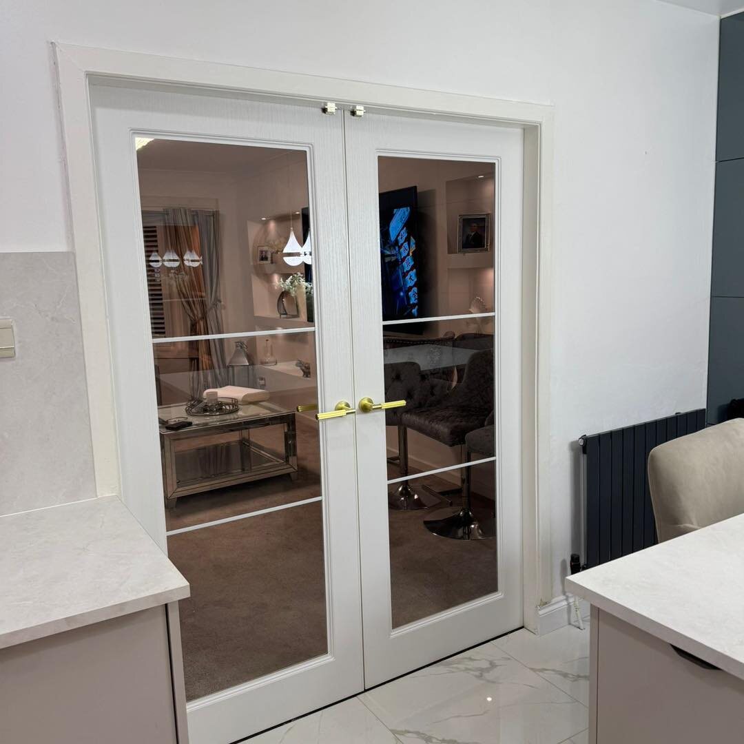White never-paint-again urban glazed French doors with gold handles, off a marble kitchen